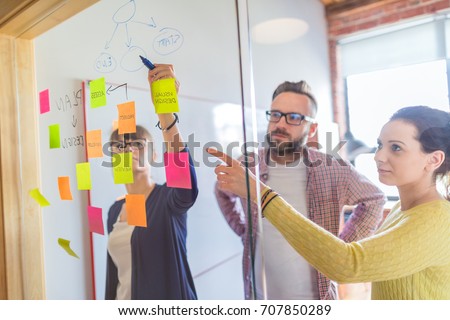 Business people meeting at office and use post it notes to share idea. Brainstorming concept. Sticky note on glass wall.