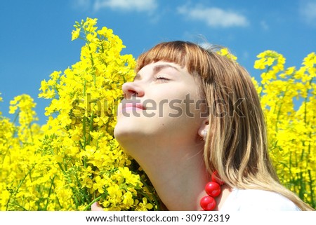 Girl resting in the rapeseed field on brilliant sky with clouds