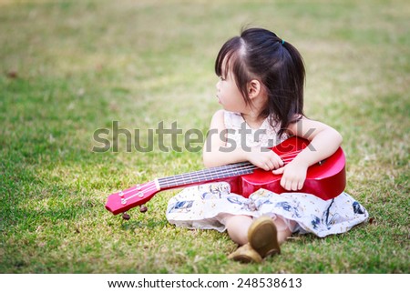 little asian girl play guitar in the garden