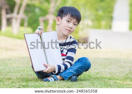 little asian boy read the book in the garden