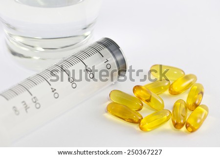 Vitamin capsules and syringe isolated white background.