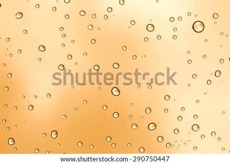 Water drop on sunset glass mirror background.