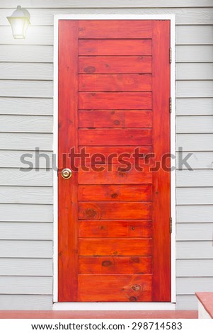 Wooden red door with lamp and wood grey texture.