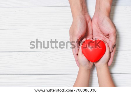 Father Day\'s and Mother\'s Day. Man holds his hands son supporting red heart.