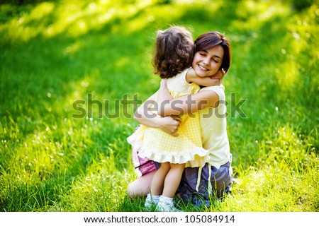 beautiful young mother and her daughter having fun on the green grass