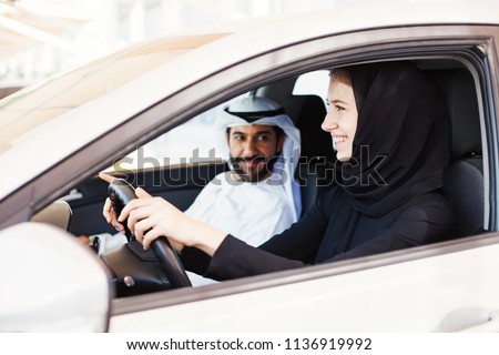 Middle eastern woman in hijab driving a car with her husband