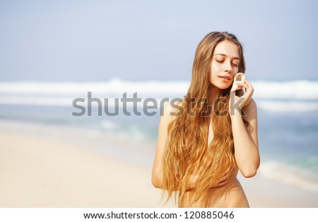 Pretty female with sea shell on beach, bali