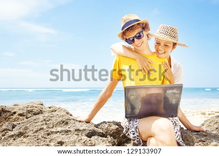 Couple of tourists on beach with laptop