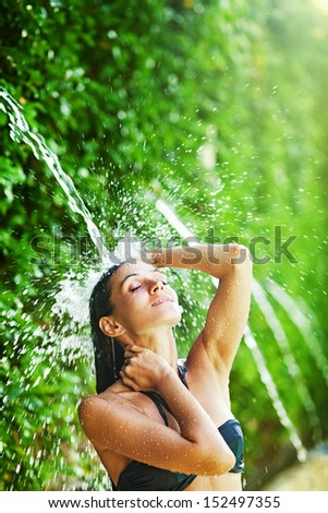 woman having shower under tropical waterfall, bali