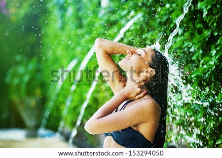 Woman Having Shower Under Tropical Waterfall, Bali