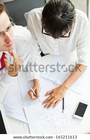 two colleagues working on project together (focus on woman\'s hands)
