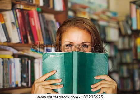 Woman hiding behind the green book - stock photo