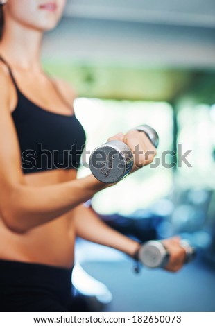 woman in gym lifting dumbbells (soft focus)