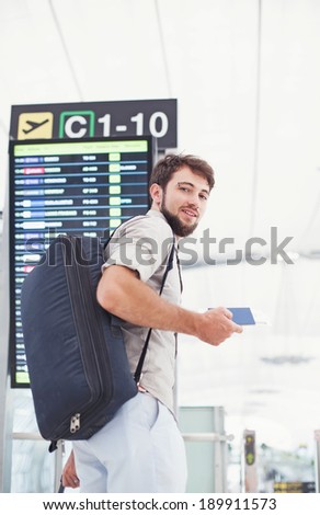 Man in airport holding his passport and hurrying for his flight near the schedule