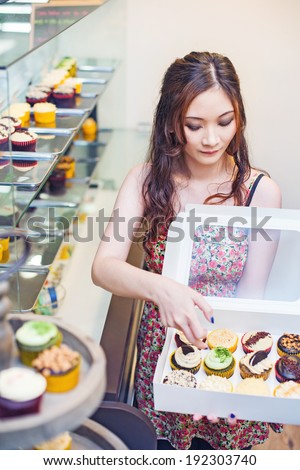 Pretty asian woman working at her own store and packing cupcakes