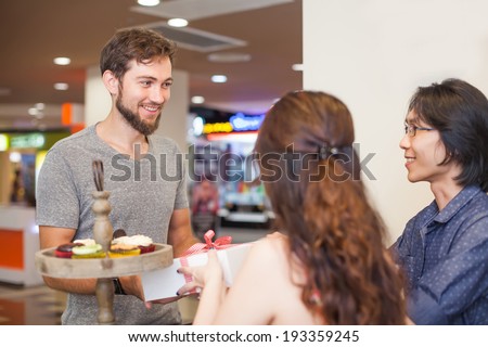 Man receiving present from sales people in the shop (focus on customer\'s eyes)
