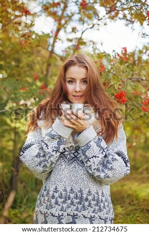 beautiful woman drinking tea from thermos in the forest