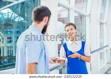 Beautiful young flight attendant checking documents of male tourist