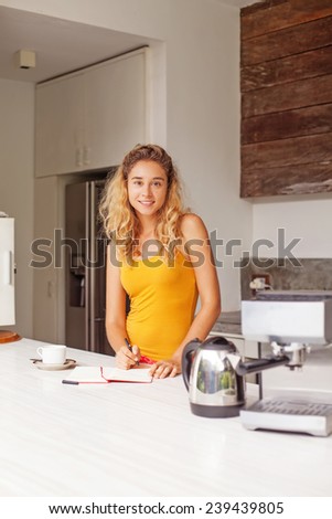 woman writing ideas for her future recipes in a kitchen