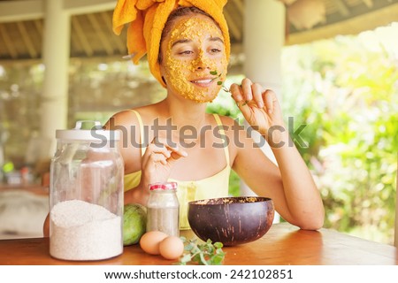 woman smelling a mint leave while doing face mask at home