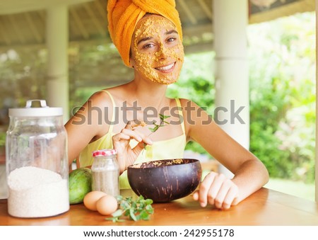 Portrait of a happy caucasian woman using natural secrets to do a skin care (ingredients are on a table: oats, flour, eggs, leaves)