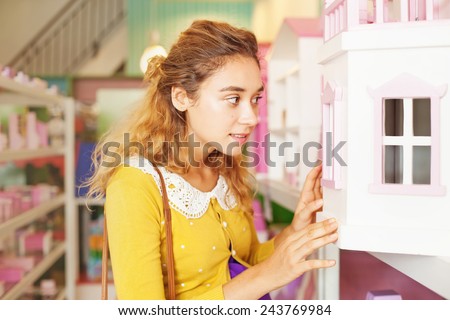 woman looking into the window of a doll house