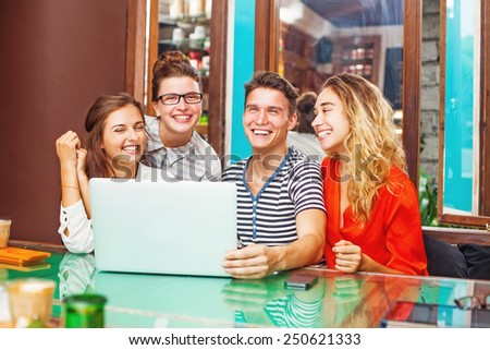 group of happy people with laptop in cafe