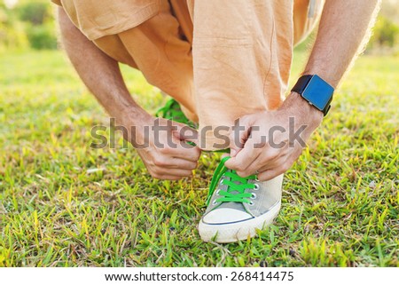 Detail of a man tying his shoe strings with a smart watch on a man's wrist. Template for sport smartwatch app design