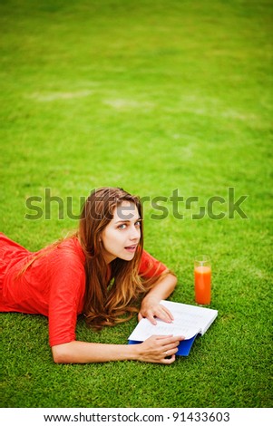 Young woman  on the grass with book and orange juice
