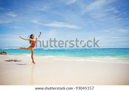 Young beautiful woman jumping over the sand near ocean, Bali, Indonesia