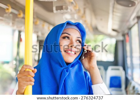 Modern muslim woman in a bus talking on mobile phone