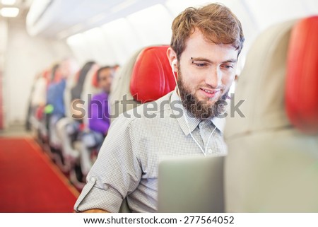 Man using laptop on board of aircraft
