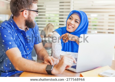 international multicultural team at work: asian muslim woman and caucasian man