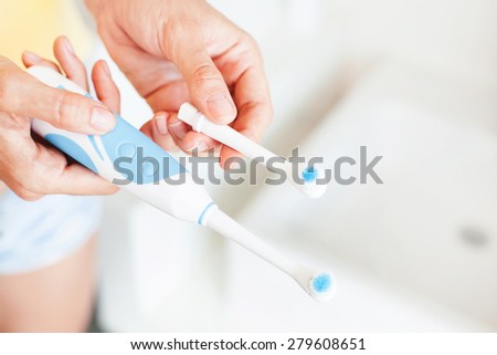 woman replacing a nozzle of an electric brush (soft focus)