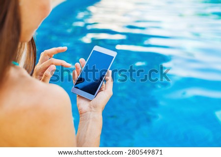 template for a smart phone app: woman using her phone while sitting at poolside