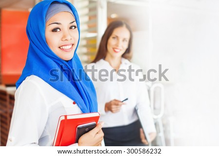muslim woman working in office with caucasian non muslim woman