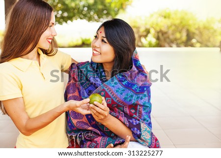 caucasian woman giving food to poor indian woman