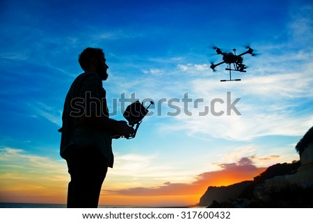 man playing with the drone. silhouette against the sunset sky