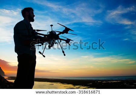 man holding a drone for aerial photography. silhouette against the sunset sky