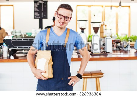 small cafe owner holding a package of coffee beans in front of the bar