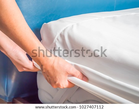Woman is putting the bedding cover or mattress pad on the bed or putting off for cleaning process.