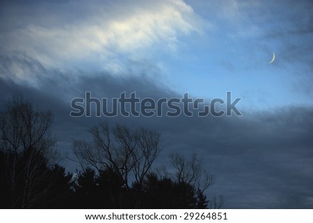 Storm clouds clear as an approaching front moves out, showing the new moon