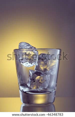 Glass with ice cubes on plain background