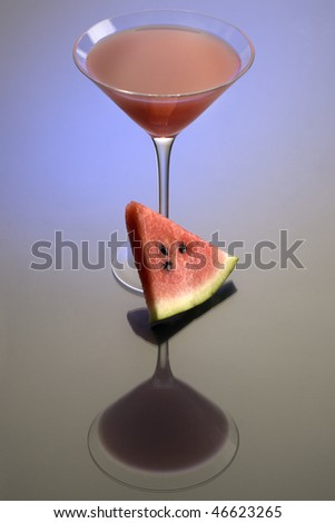 Watermelon Martini mixed drink with melon garnish on grey background with reflection