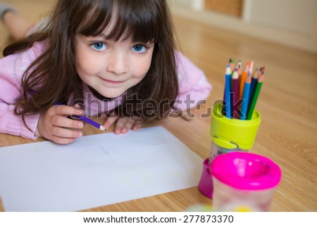 Baby girl with big cute blue eyes drawing