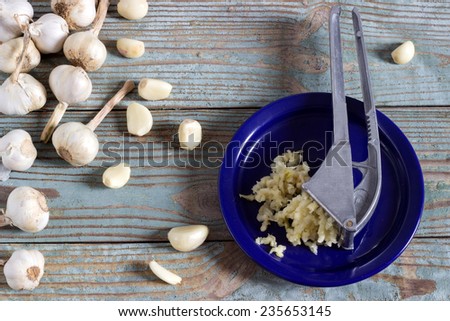 crushed fresh garlic press on a wooden board