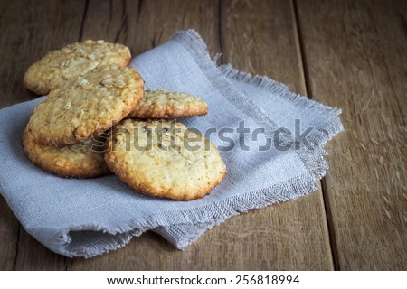 oatmeal cookies on white linen napkin on wooden table. Chocolate chip cookies shot on coffee colored cloth, closeup.
