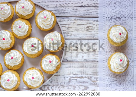 Cupcakes with white cream on a plate with decoration heart wooden white background