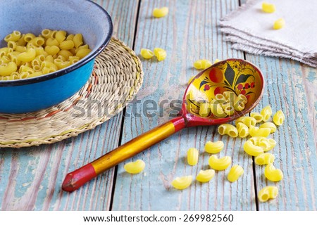 dry pasta on a wooden table in an iron bowl with a wooden spoon