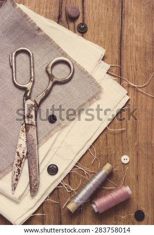 Vintage Background with sewing tools and colored tape Sewing kit. Scissors, bobbins with thread and needles on the old wooden background toning
